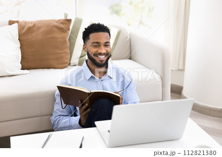 Happy positive young Black student guy studying online at home Happy positive young Black student guy studying online at home 112821380