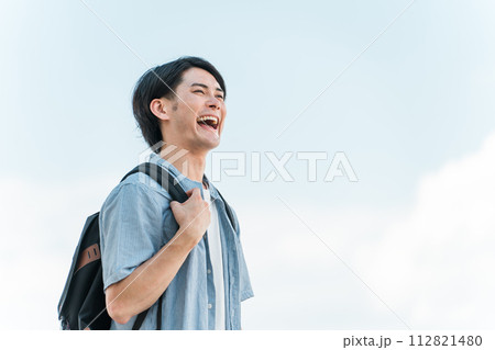 青空の下にいる笑顔の学生・大学生の男性(進学・受験・チャレンジ・希望・目標) 青空の下にいる笑顔の学生・大学生の男性(進学・受験・チャレンジ・希望・目標) 112821480