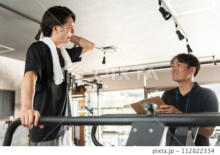 スポーツジムでパーソナルトレーニングを受ける男性とインストラクター・トレーナー・理学療法士 112822334