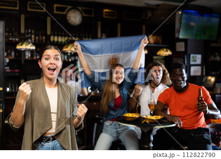 Happy international fans waving the flag of Argentina, drinking beer, watching football match in the bar 112822790