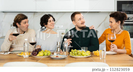 Two married couples are sitting at table, enjoying food and wine, chatting, talking, laughing. Two married couples are sitting at table, enjoying food and wine, chatting, talking, laughing. 112823059