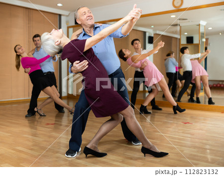Couple of mature dancers rehearsing ballroom dances in dance studio 112823132
