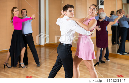 Couple of young dancers rehearsing ballroom dances in dance studio Couple of young dancers rehearsing ballroom dances in dance studio 112823145