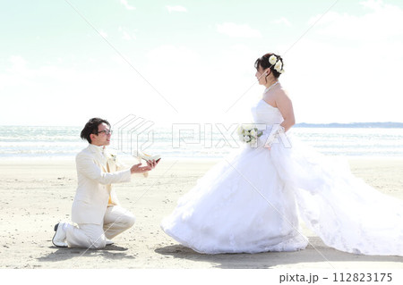ウエディングドレス姿の新婦様とタキシード姿の新郎様フォトウエディング、海でのロケーション撮影 112823175