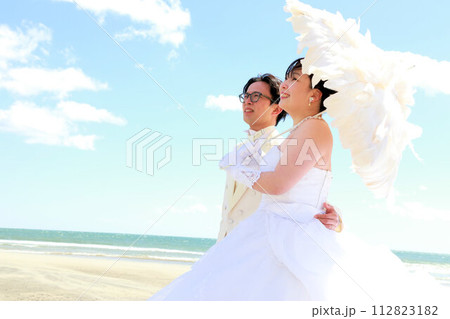 ウエディングドレス姿の新婦様とタキシード姿の新郎様フォトウエディング、海でのロケーション撮影 112823182