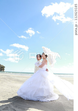 ウエディングドレス姿の新婦様とタキシード姿の新郎様フォトウエディング、海でのロケーション撮影 112823185