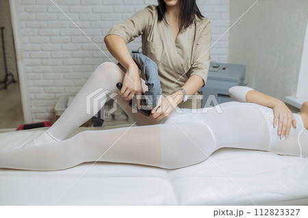 Beautiful woman getting beauty therapy against cellulite with LPG machine on her butt. LPG massage for lifting body. Beautiful woman getting beauty therapy against cellulite with LPG machine on her butt. LPG massage for lifting body. 112823327