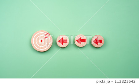 Circular wood with printed target icons and business symbols on green background, business goals and objectives concept, business competition. 112823642