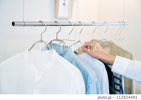 ハンガーにかかったメンズの洋服と手 112824491