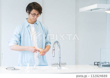 キッチンで食器を洗う若い男性 キッチンで食器を洗う若い男性 112824689