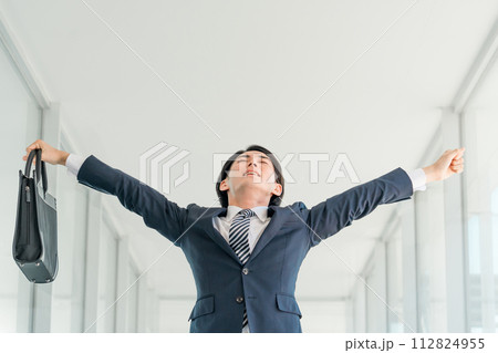 仕事終わりに伸び・ストレッチをするスーツ姿の若いアジア人男性ビジネスマン(解放・残業・緊張) 仕事終わりに伸び・ストレッチをするスーツ姿の若いアジア人男性ビジネスマン(解放・残業・緊張) 112824955