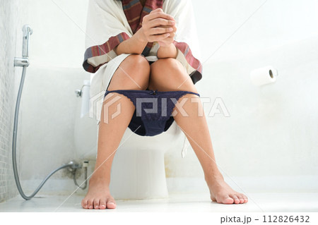 Man sitting in the toilet bowl. In the bathroom, his home is unhappy with constipation, diarrhea, food poisoning, health and medical concepts. Man sitting in the toilet bowl. In the bathroom, his home is unhappy with constipation, diarrhea, food poisoning, health and medical concepts. 112826432