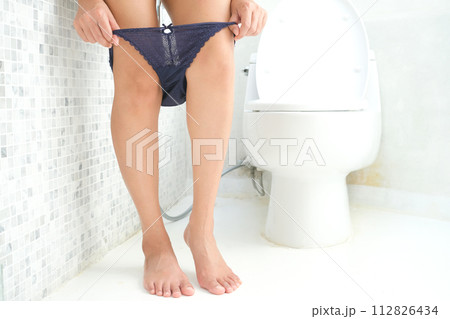 A woman takes off her purple panties in the bathroom. She has a stomachache and is dissatisfied with constipation, diarrhea, food poisoning, background, toilet bowl. health and medicine A woman takes off her purple panties in the bathroom. She has a stomachache and is dissatisfied with constipation, diarrhea, food poisoning, background, toilet bowl. health and medicine 112826434