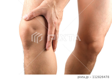 Knee pain. Young man's leg. He uses his hands to hold and massage the knee area. with tendon pain and knee joint muscles to relieve pain health concept Knee pain. Young man's leg. He uses his hands to hold and massage the knee area. with tendon pain and knee joint muscles to relieve pain health concept 112826478