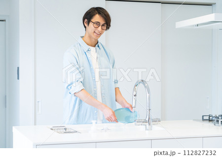 キッチンで食器を洗う若い男性 キッチンで食器を洗う若い男性 112827232