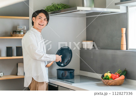 キッチンのHIコンロで煮込み料理をする若い男性(自炊・料理男子) キッチンのHIコンロで煮込み料理をする若い男性(自炊・料理男子) 112827336