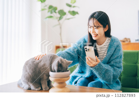 ごはんを食べる猫を撫でる女性 ごはんを食べる猫を撫でる女性 112827893