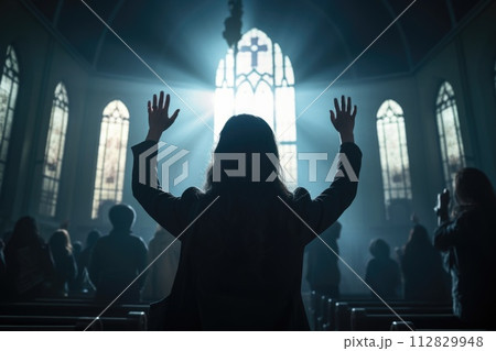 Capturing divine moments: church worship concept Christians, raised hands, earnestly pray and worship to cross in the sacred ambiance of a church building, expressing faith and spiritual connection. 112829948