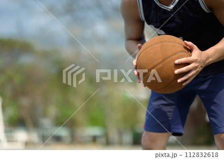 Cropped shot of sportsman dribbling the ball on an outdoor court. People, sport and active lifestyle concept Cropped shot of sportsman dribbling the ball on an outdoor court. People, sport and active lifestyle concept 112832618