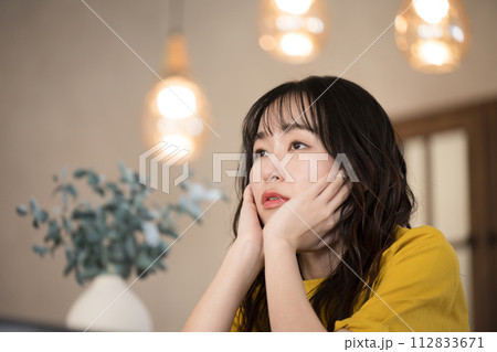 夜の部屋で頬杖をつく若い女性 夜の部屋で頬杖をつく若い女性 112833671