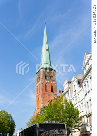 Close-up view of spire steeple of St Jakobi gothic church with clocks in old Lubeck town center. UNESCO heritage city altstatd in Germany travel destination 112834325
