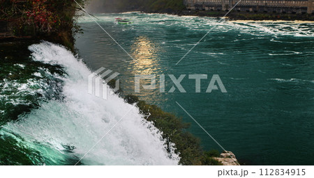 Evening at Niagara Falls. The river reflects the setting sun, in the foreground a powerful stream of water. Slow motion 120 fps video 112834915