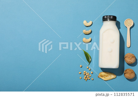 Bottle of alternative milk and herbal ingredients on blue background, space for text Bottle of alternative milk and herbal ingredients on blue background, space for text 112835571