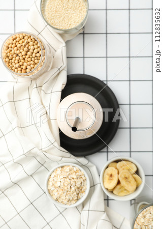 Bottle with alternative milk, towel and bowls with ingredients on light background, top view 112835632