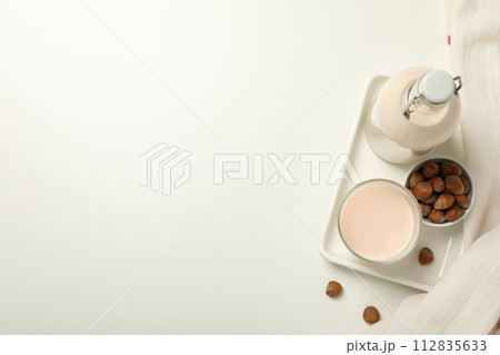 Bottle and glass with milk, towel and bowl with nuts on white background, space for text 112835633