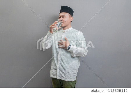 Happy asian muslim man drinking a fresh glass of pure water 112836113