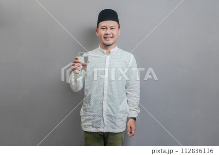 Happy asian muslim man holding glass of pure water give to camera 112836116