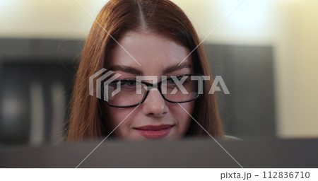 Redhead woman in glasses, face and computer screen, reading and smiling, editor working from home. Research, analysis and remote work with women. 112836710