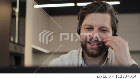 Closeup face man wearing headset and talking, call center worker. Positive young man wearing headset. Phone assistance service concept. 112837014