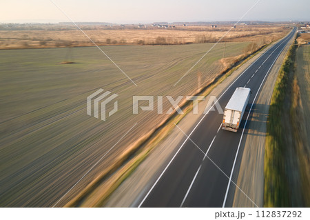Aerial view of blurred fast moving semi-truck with cargo trailer driving on highway hauling goods in evening. Delivery transportation and logistics concept 112837292