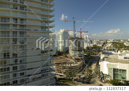 Tower lifting cranes at high residential apartment building construction site. Real estate development in Miami urban area 112837317
