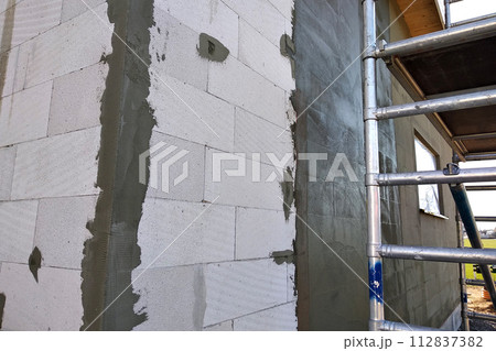 Facade of white block building under construction works. Facade of white block building under construction works. 112837382