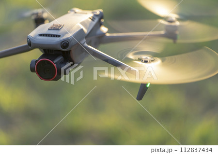 Drone aircraft with blurred fast rotating propellers and video camera flying in air Drone aircraft with blurred fast rotating propellers and video camera flying in air 112837434