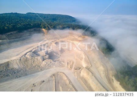 Aerial view of open pit mining of limestone materials for construction industry with excavators and dump trucks. Aerial view of open pit mining of limestone materials for construction industry with excavators and dump trucks. 112837435