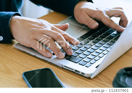 自宅でパソコンを操作するミドル男性の手元 112837901