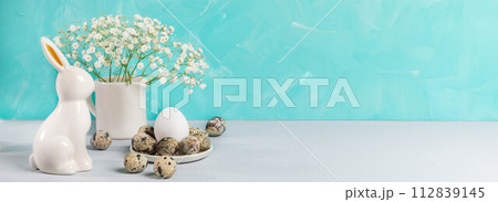 Easter banner in white turquoise colors. Quail eggs, ceramic bunny, white gypsophila. Copy space. 112839145