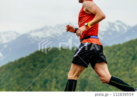close-up man running in background of mountains and forests, with timer on his arm close-up man running in background of mountains and forests, with timer on his arm 112839554