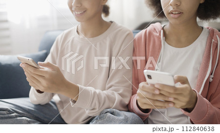 African American sisters using social network app on smartphones, teenagers 112840638