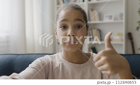 African American teenager creating content, talking to subscribers online, showing like gesture on camera 112840655