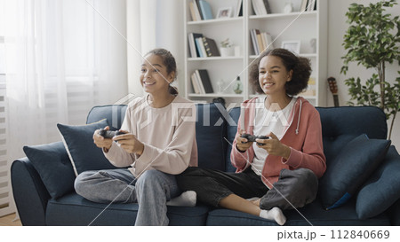 Happy teen sisters sincerely smiling, playing video game together, relationship 112840669