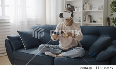 Teen girl wearing virtual reality headset, playing game at home, modern technology Teen girl wearing virtual reality headset, playing game at home, modern technology 112840675