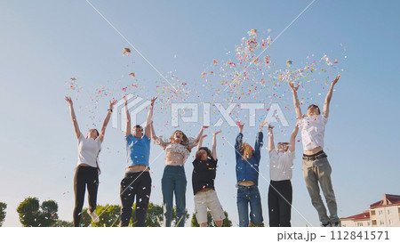 Friends toss colorful paper confetti from their hands. 112841571