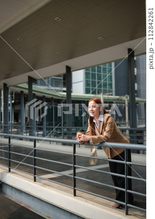 A Business Woman wearing a suite standing and waiting for customers on the balcony. 112842261