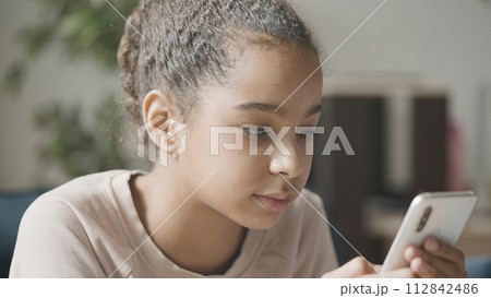Happy teen girl sending text message on smartphone, enjoying communication 112842486