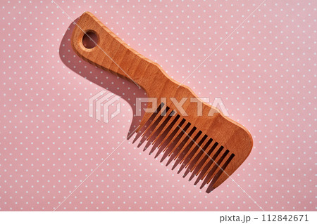 Wooden comb on a pink polka dot background. 112842671