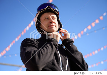 Skier Securing Helmet Under Sunny Sky Skier Securing Helmet Under Sunny Sky 112843928